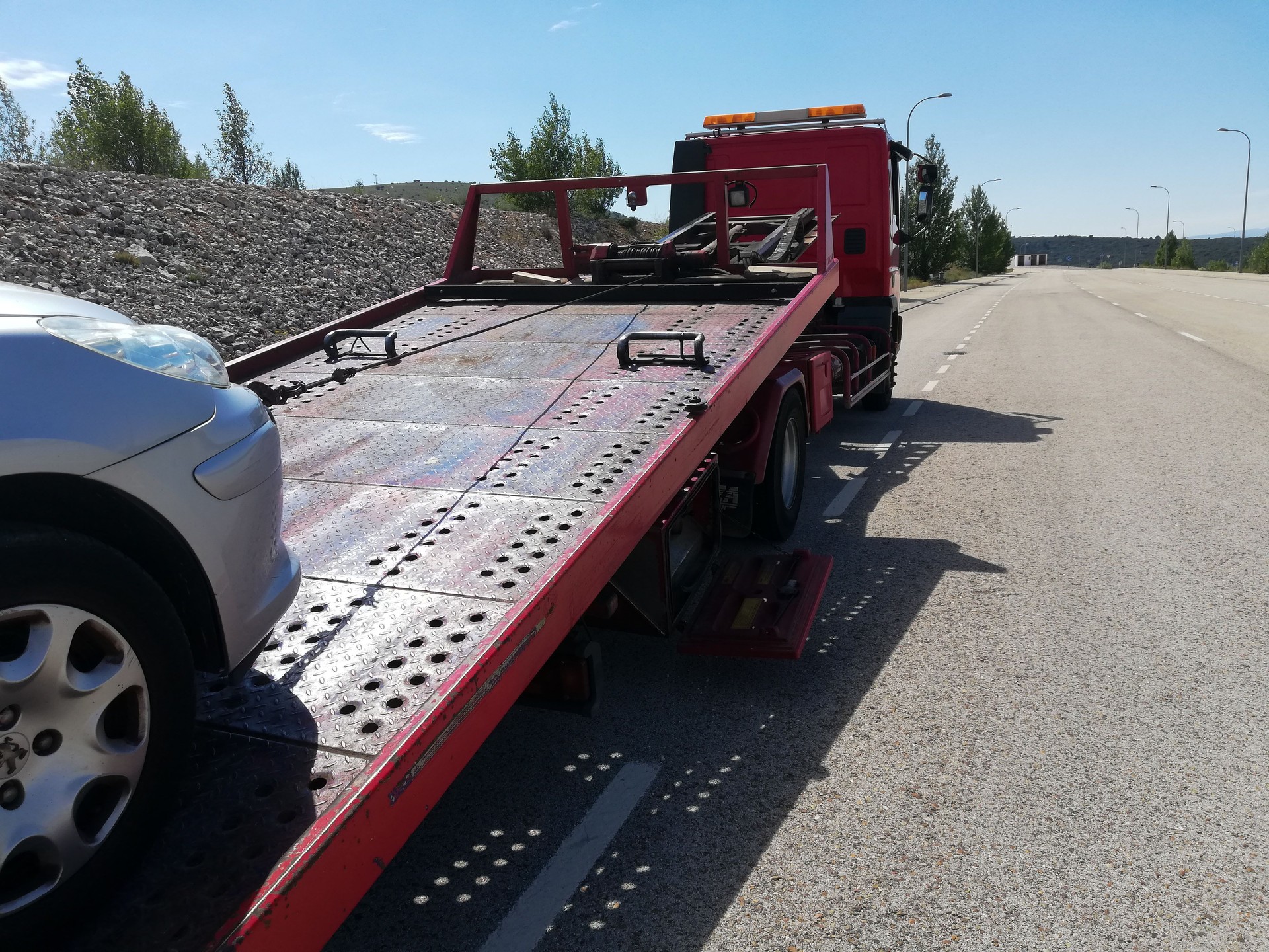 detail of a tow truck towing a damaged car in the middle of the street